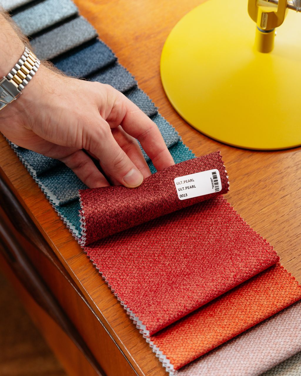 Lifting a fabric sample from a collection on table